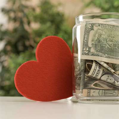 A photograph of a felt heart next to a jar of paper money.