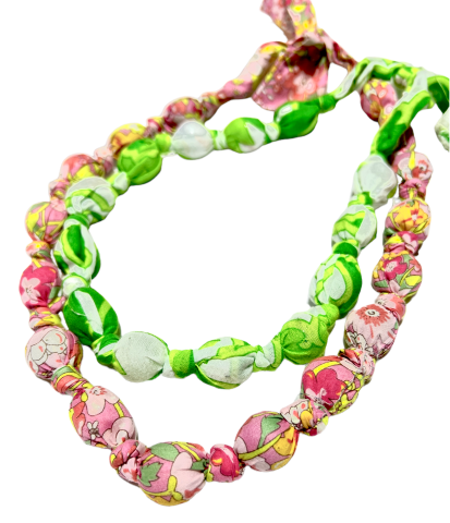 2 fabric beaded necklaces, one in green and one in pink laying on top of one another