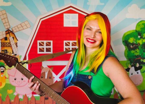 musician holding guitar in front of barnyard 