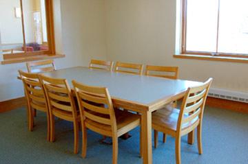 Sunny room with a table in the center surrounded by 8 chairs.