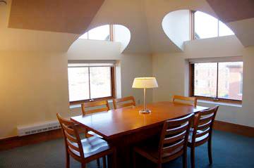 Room with table in the center with two big windows on the far walls.