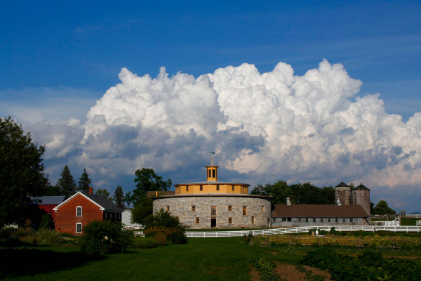 A round building surrounded by various buildings on a cloudy day.