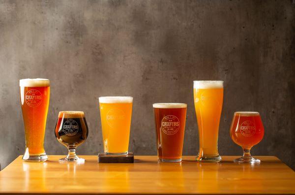 A lineup of beers in a row with different sizes of glasses