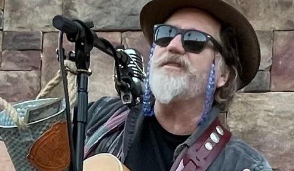 an image of the bluesman, Ramblin' Dan Stevens, as he strums his guitar with sunglasses on.