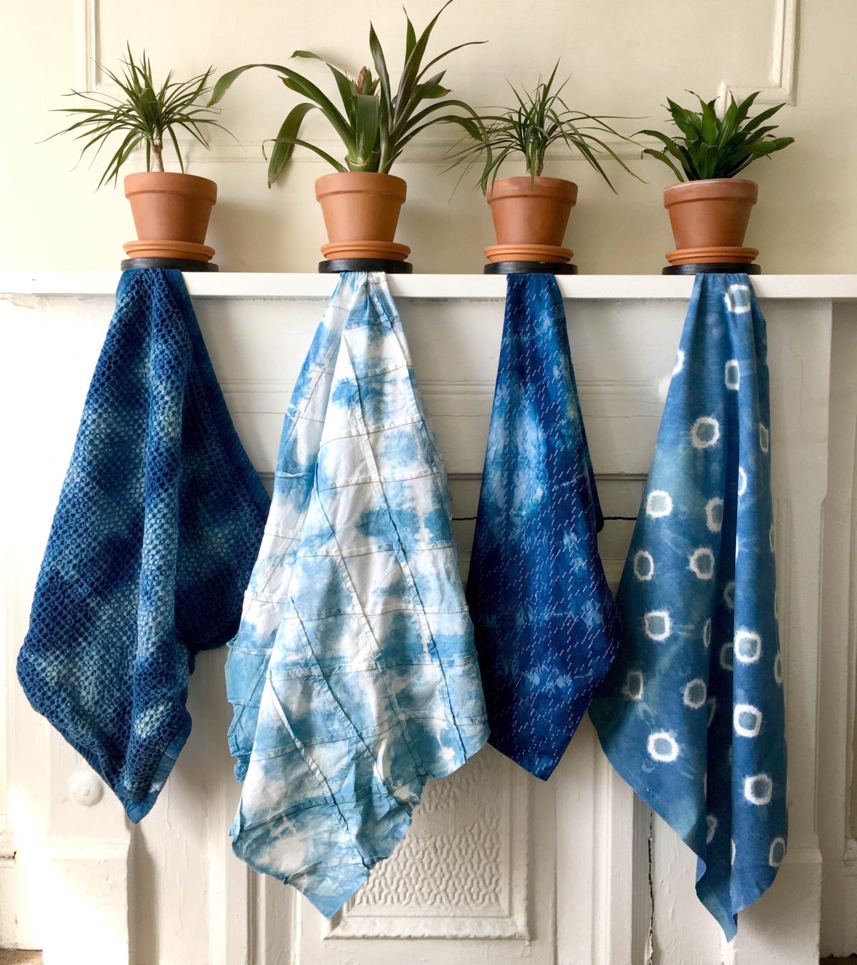 Four Shibori indigo dyed tea towels hanging underneath potted plants