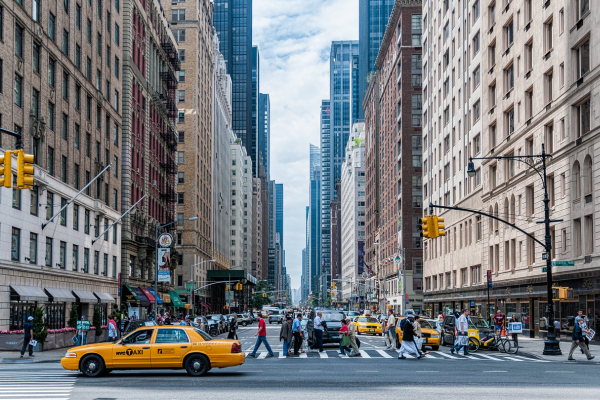 A NYC street, tall buildings, yellow taxicab. 